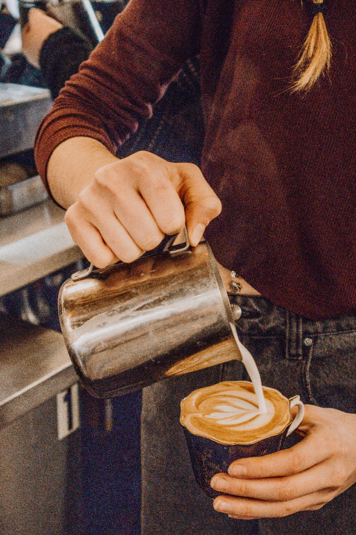 FeelLove barista pouring latte art into a branded cup.
